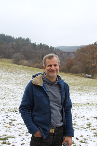 Auf dem Bild sieht man Thomas Väth, der in der verschneiten Landschaft von Hetzbach steht. Im Hintergrund das Himmelbächer Viadukt.